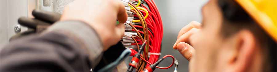 Worker adjusting wires in industrial Control panel